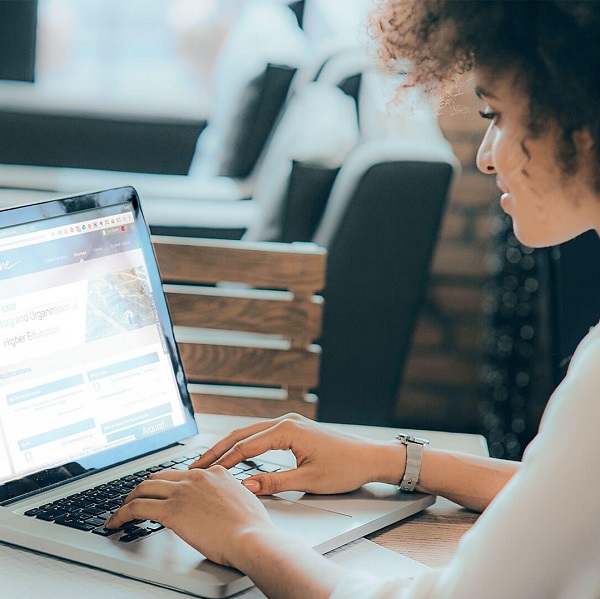 A woman uses a laptop that has SHSU Online's Blackboard on the screen.